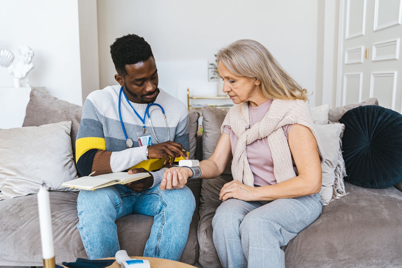 Profesional de la salud con credencial tomando la presión a una paciente en el living de su casa